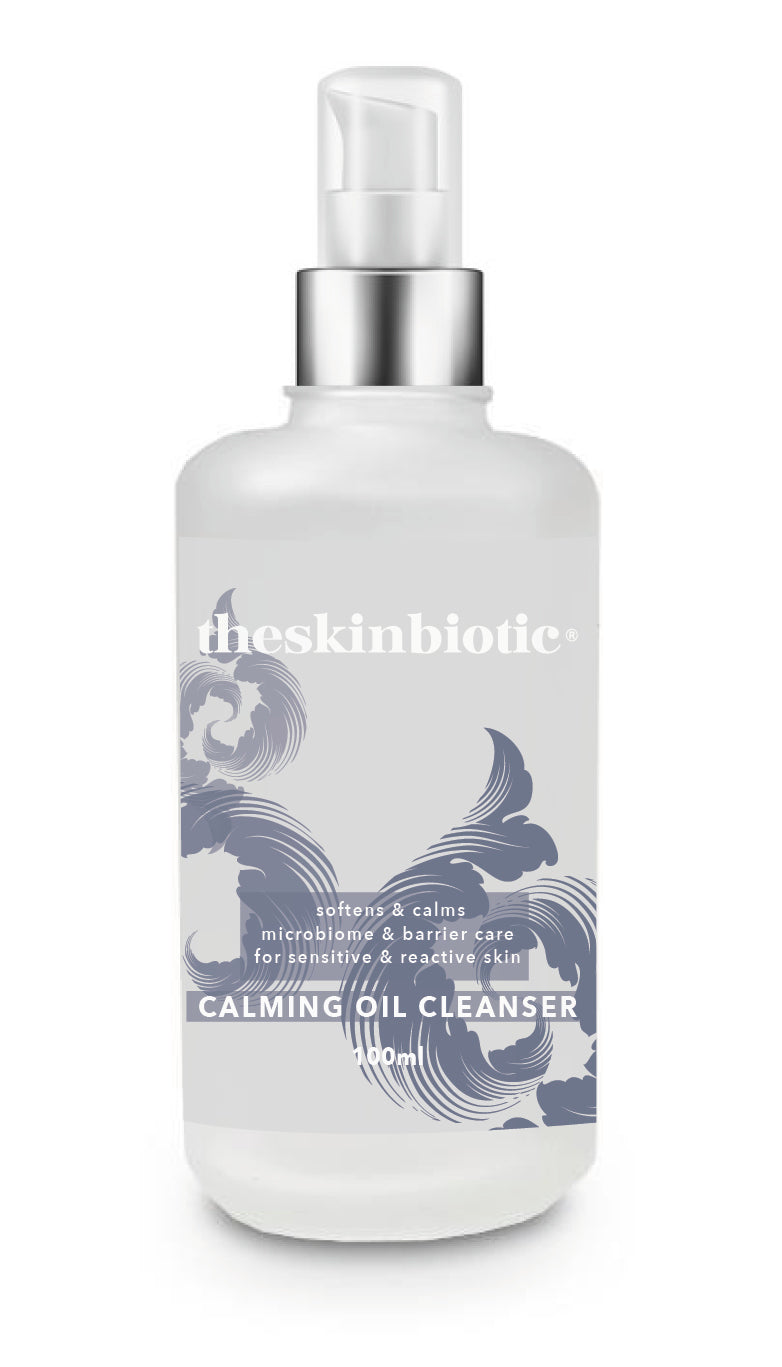 Bottle of Calming Cleansing Oil by theSkinBiotic® clear frosted glass bottle with white writing and navy swirls . Cleanser softens and calms with both microbiome and barrier care, especially for sensitive and reactive skin. By Microbiome skincare brand theSkinBiotic.