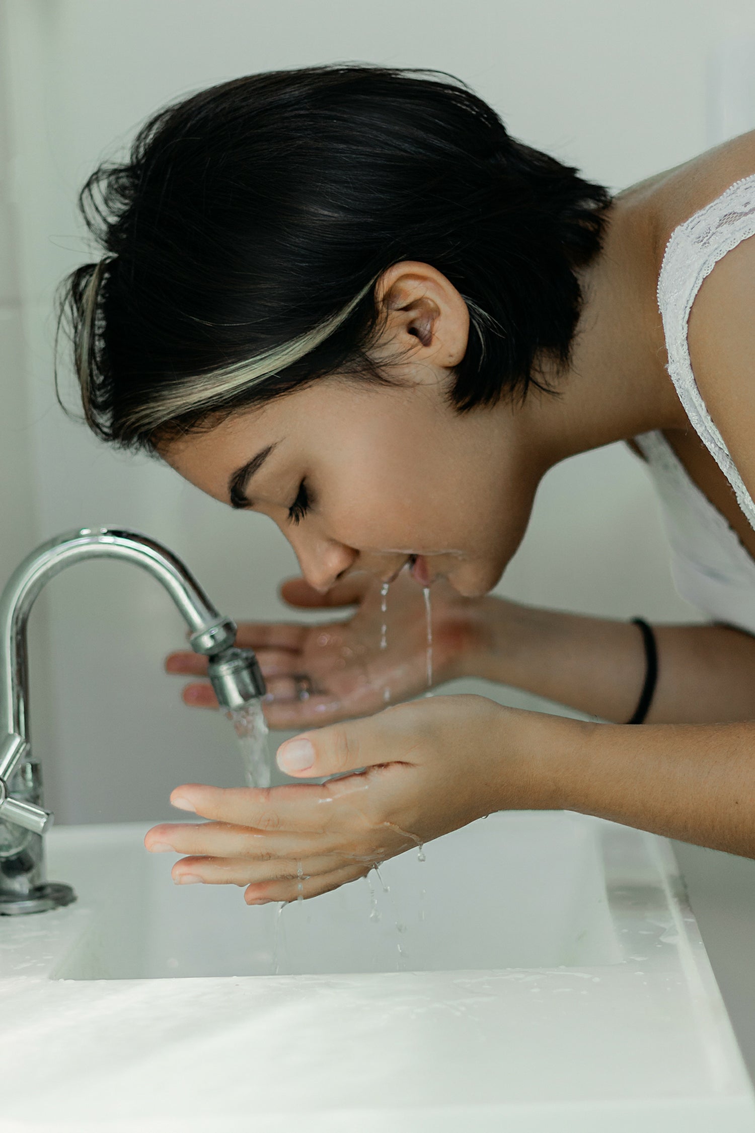 girl with face over bathroom basin cleaning with theSkinBiotic Calming Cleansing Oil